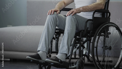 Sad man with disabilities sitting in wheelchair alone, suffering loneliness