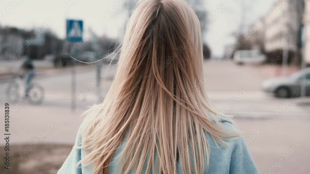 Back view woman with long blonde hair walking. Businesswoman in blue coat with beautiful long fair hair. Slow motion. Back view woman with long blonde hair walking. Businesswoman in blue coat with beautiful long fair hair. Slow motion.