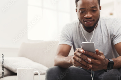 Young african-american man in earphones with mobile