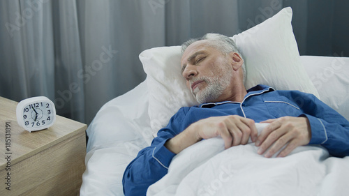 Senior man sleeping in bed in the morning, healthy rest during recovery time photo