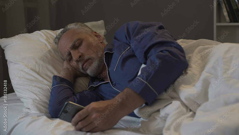 Fototapeta premium Addicted to smartphone retired man scrolling application instead of sleeping