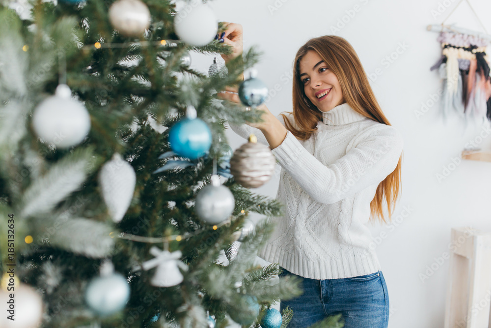 A beautiful girl is decorating a christmas tree. A beautiful girl is decorating a christmas tree.
