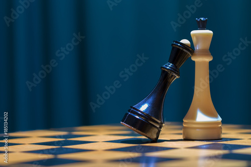 Foto Chess black queen and white king stand on a wooden chessboard