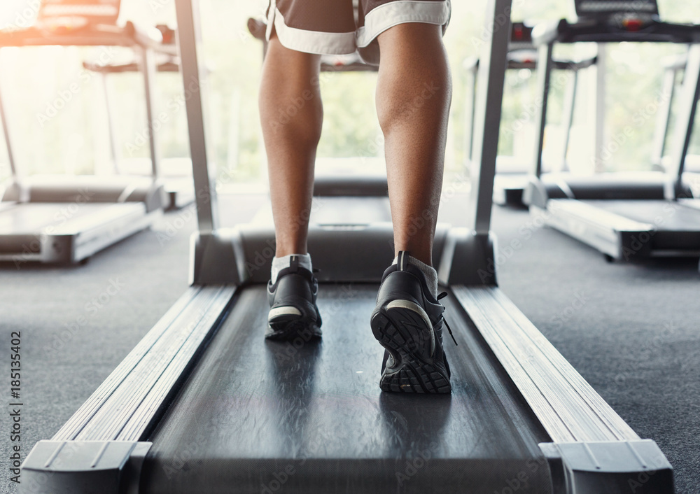 Man's feet on treadmill in fitness club, healthy lifestyle