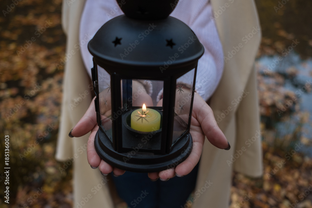 woman's hands Holding black candle lantern in the forest.