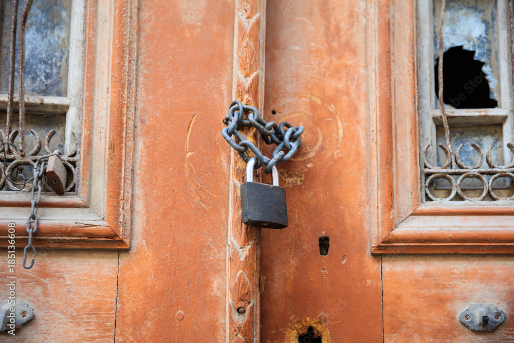 Rusty padlock on an old wooden door with broken window. Close up view with details. Rusty padlock on an old wooden door with broken window. Close up view with details.