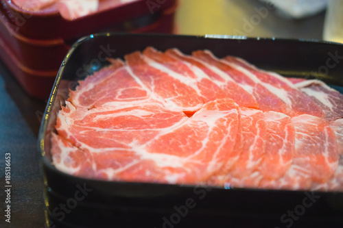 Raw pork chop meat sliced on black plate.