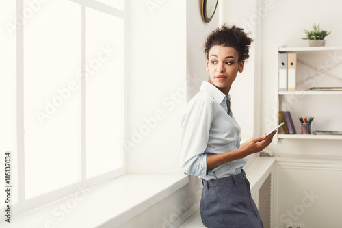 Business woman with mobile phone near office window