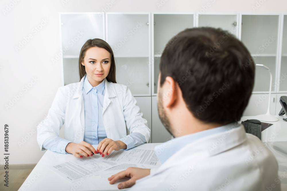 Two doctors talking while sitting in the clinic office. Two doctors talking while sitting in the clinic office.