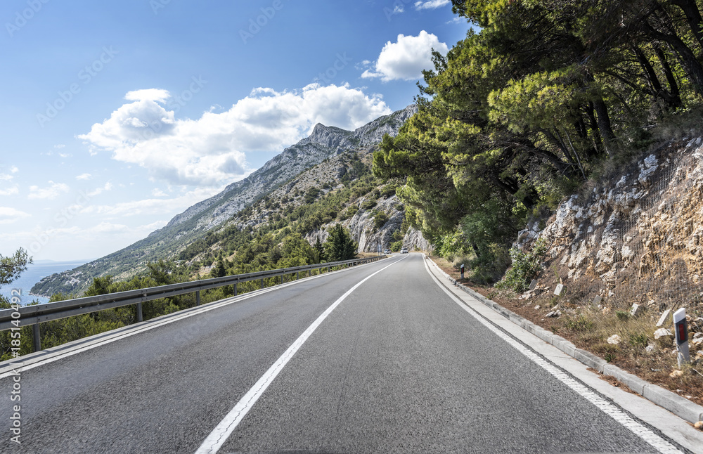 Naklejka premium Country road through the rocky mountains and forest.