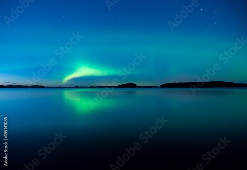Northern lights dancing over calm lake in Farnebofjarden national park in Sweden