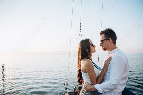 Young married couple spend their honeymoon on the sea on a yacht, hugging each other 