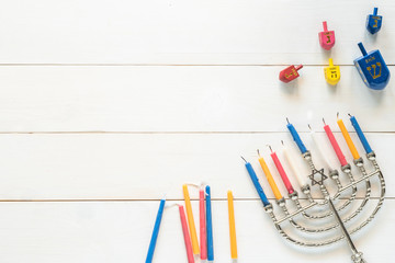 Hanukkah/ Chanukah Jewish holiday background with menorah (Judaism candelabra) burned candles and traditional Dreidrel game toy on white wood table backdrop
