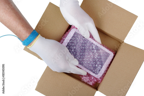 The technician in antistatic gloves takes out a tablet spare part from the industrial package photo