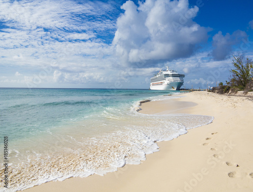 A cruise ship docks in Grand Turk with waves and sand in the foreground.