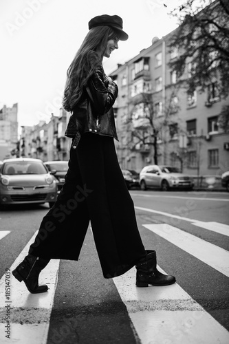 Beautiful girl with sunglasses. A model in a stylish wide-brimmed hat at a pedestrian crossing. Harmoniously similar clothes in gray tones. Street style shooting. Women's fashion. photo