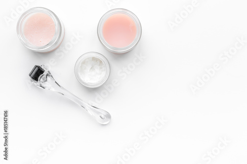 Cosmetoligist's instruments. Dermaroller and cosmetics mask and cream on white background top view copyspace