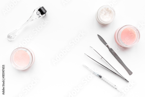 Dermatologist or cosmetologist accessories. Dermaroller, creams and mask, beauty injection, tools on white background top view copyspace