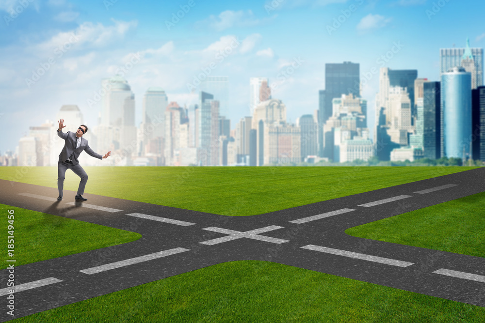 Young businessman at crossroads in uncertainty concept Young businessman at crossroads in uncertainty concept