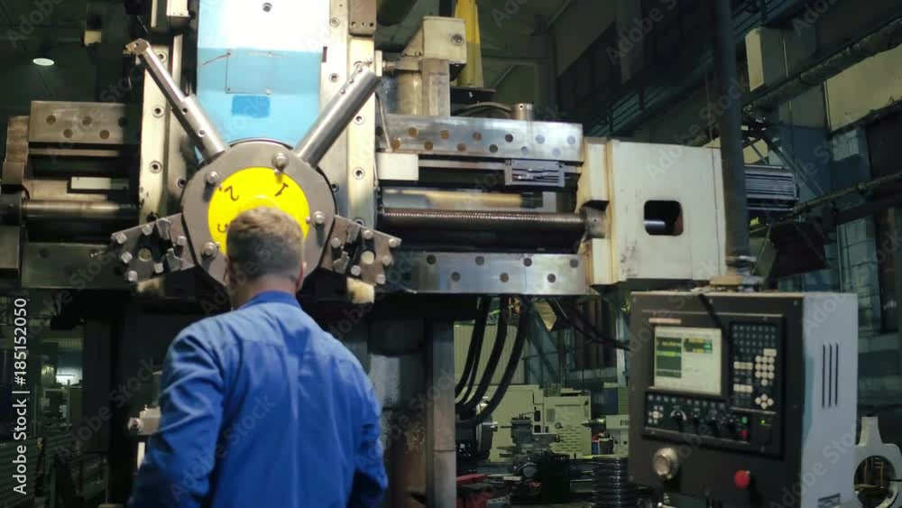 Employee using professional metalworking lathe with electronic remote control Employee using professional metalworking lathe with electronic remote control