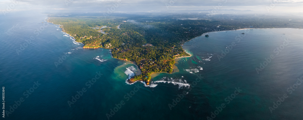 Aerial panorama of the cape of the town of Weligama with fisherman boats, beaches and waves breaking on the reef. Sri Lanka
