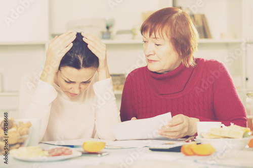 Unhappy women with documents sitting at table