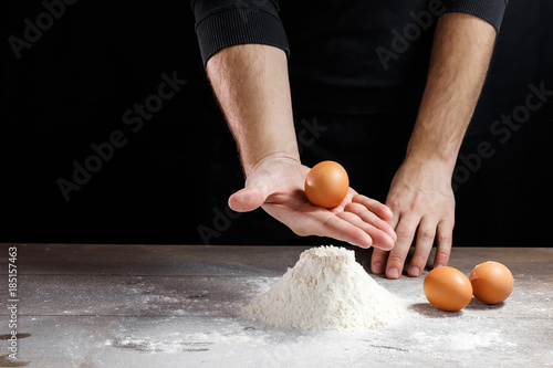 Male hand chef close-up. Preparation of Italian food pasta, pizza or bread focaccia. The recipe for cooking home-made dishes from the chef. Dark background. photo