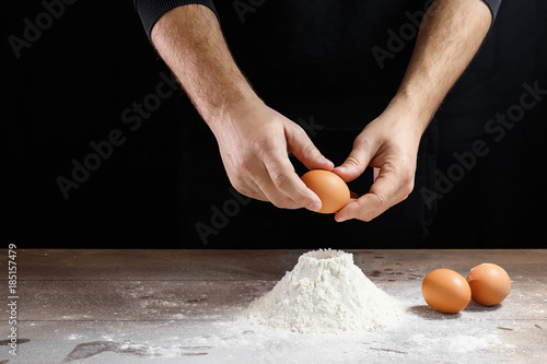 Male hand chef close-up. Preparation of Italian food pasta, pizza or bread focaccia. The recipe for cooking home-made dishes from the chef. Dark background. photo