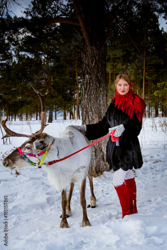 girl and reindeer in the winter forest