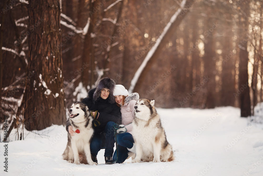 Walking with dog in winter. Lover couple is walking in snow with dog. Sun light Walking with dog in winter. Lover couple is walking in snow with dog. Sun light