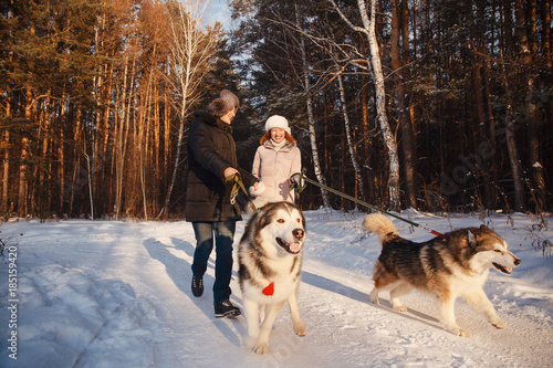 Walking with dog in winter. Lover couple is walking in snow with dog. Sun light
