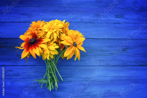Bouquet of bright summer flowers on colorful wooden boards.