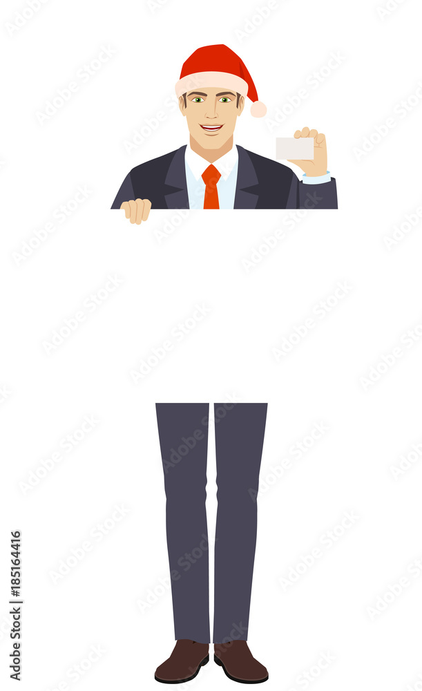 Businessman in Santa hat holding white blank poster and showing the business card Businessman in Santa hat holding white blank poster and showing the business card