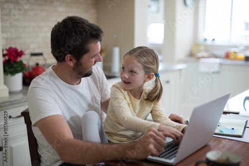 Father and daughter working on laptop 