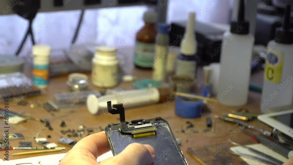 A man's hand repairing a smartphone A man's hand repairing a smartphone