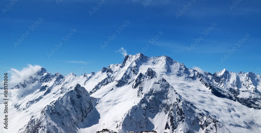 Naklejka premium Panoramic view of snow covered mountain peaks and beautiful blue sky