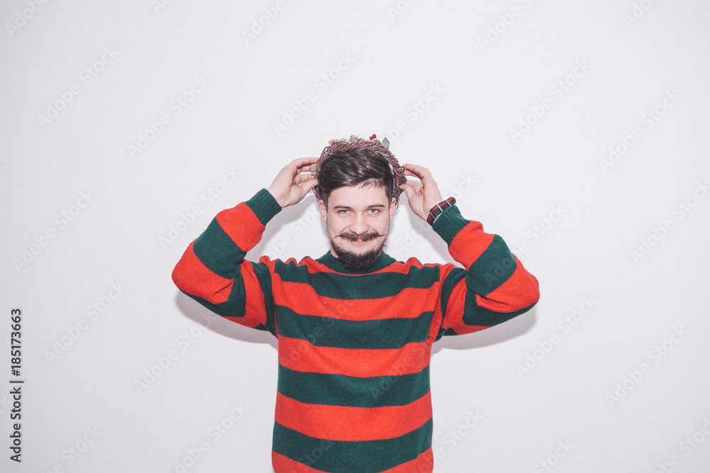 funny boy wearing warm sweater and christmas wreath on white background funny boy wearing warm sweater and christmas wreath on white background