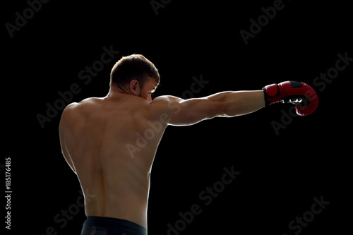 Fighter training on his own. Young man throwing kicks with boxing gloves on hands. Preparing for a match.