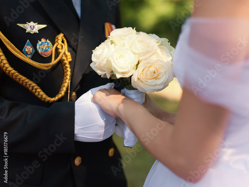 Hands of officer in gloves and bride with wedding bouquet