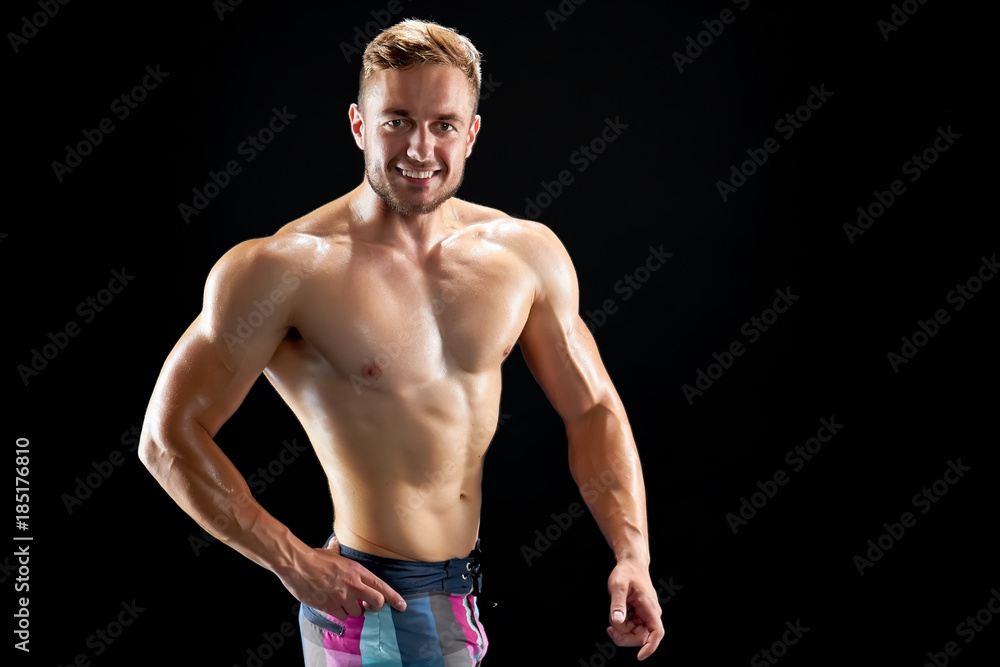 Fototapeta premium Successful athlete posing on black. Gorgeous smile and sexy muscular body. Exercise and nutrition. Fitness and wellness.