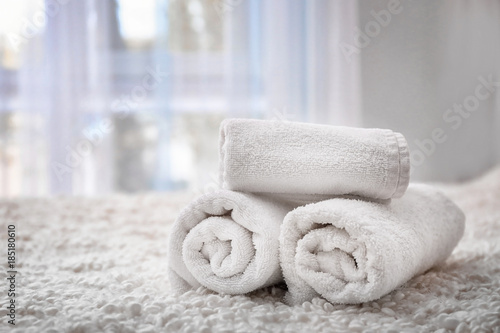 Rolled bath towels on bed in hotel suite