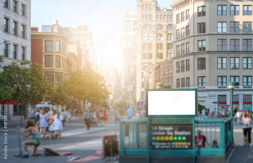 Fototapeta premium Tłum ludzi chodzących w Union Square Park w pobliżu stacji metra 14th Street na Manhattanie w Nowym Jorku z pustym znakiem billboardu i świecącym światłem słonecznym w tle