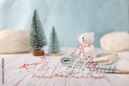 A small white toy bear is sitting on a pile of socks photo