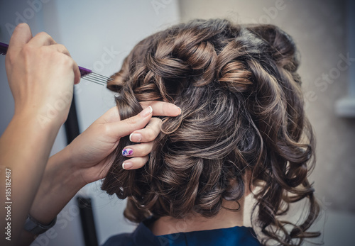 The hands of the hairdresser do wedding hairstyle