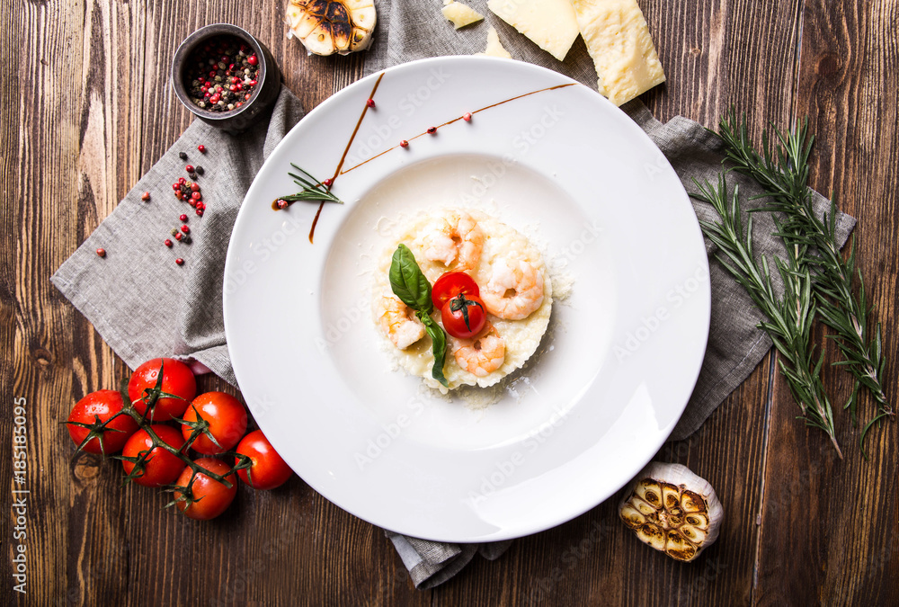 Risotto with shrimps in a white plate on a dark wooden background top view Risotto with shrimps in a white plate on a dark wooden background top view