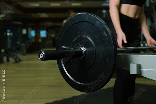Close-up of a woman holding her hands with a barbell for pulling, squatting, fitness in the gym. Concept sports, toned picture, copyspace for text