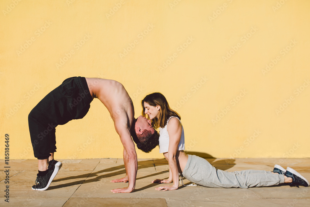 © BONNINSTUDIO/Stocksy - Couple in love doing acrobatics in front of a yellow wall.