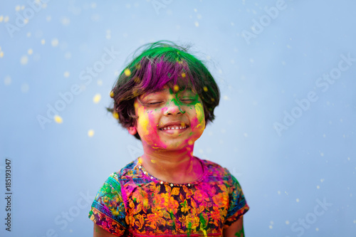 Portrait of cute little girl being showered by colored powders during holi