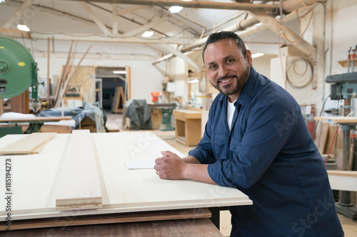 Side portrait of smiling hispanic cabinet shop worker