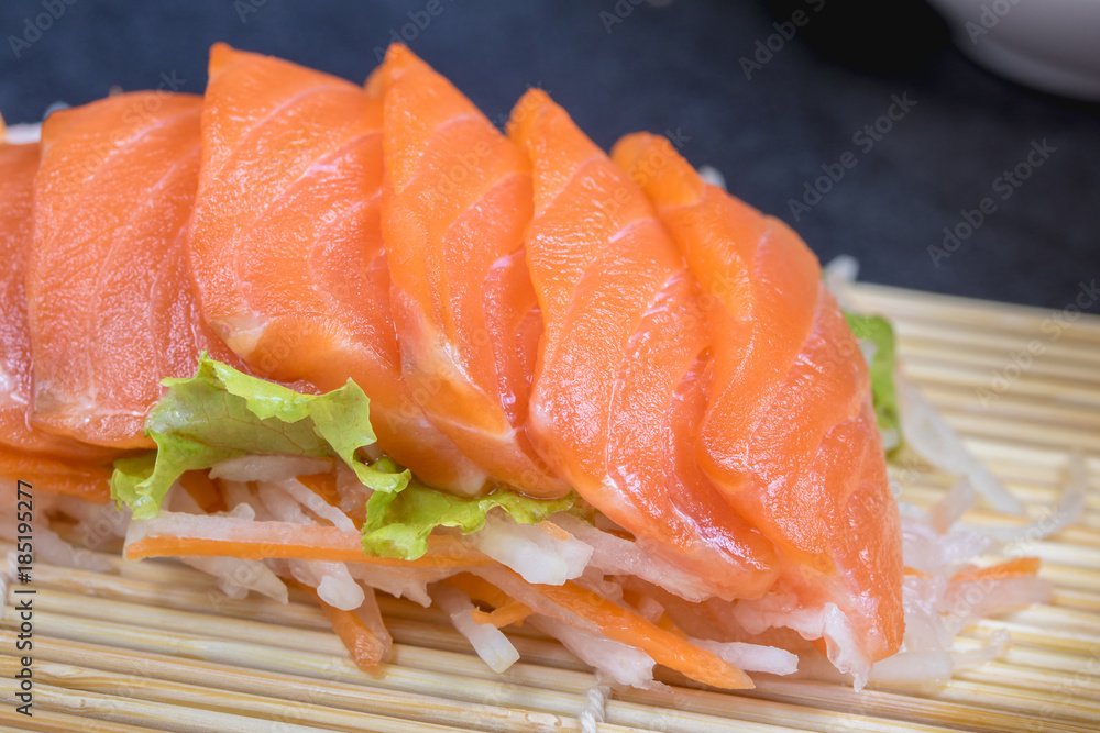 Close up raw fresh salmon sashimi set salad  on black table.